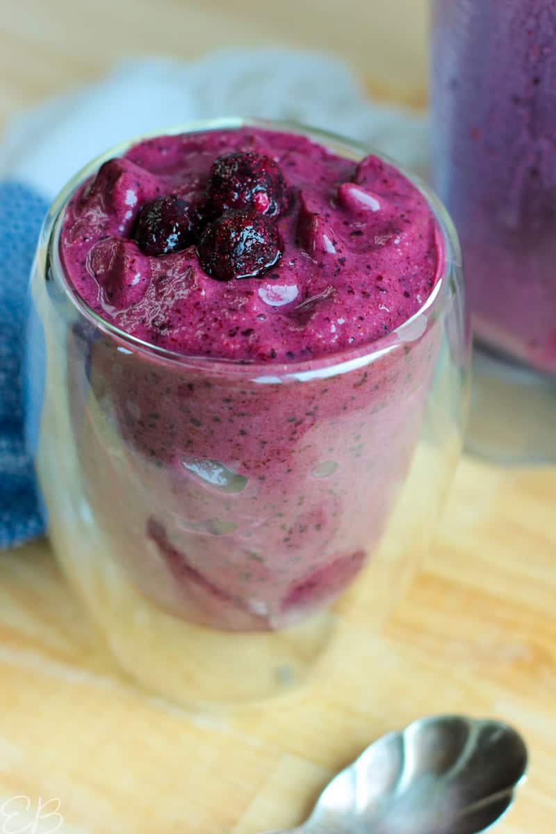side angle view of best blueberry smoothie in glass with blender in the background