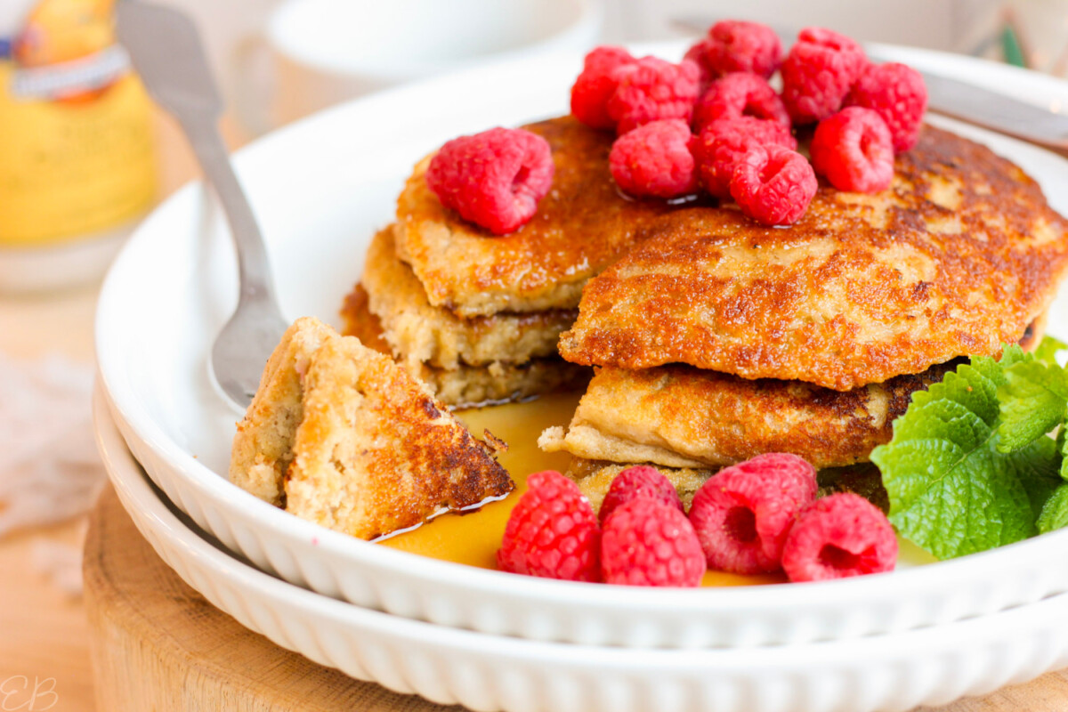 gluten free vegan Oat Flour Pancakes cut into with maple syrup and raspberries on top