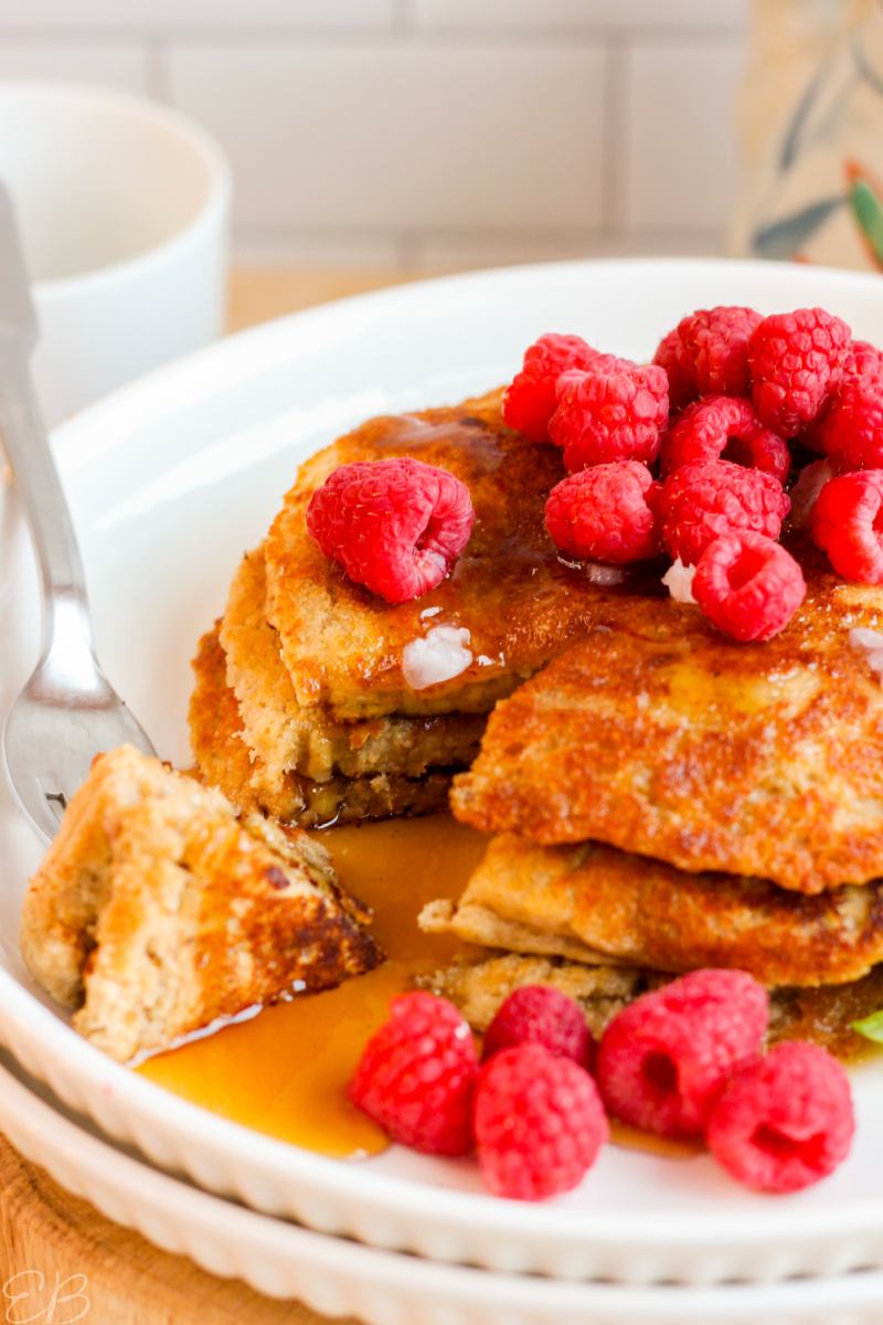gluten free vegan Oat Flour Pancakes cut into with maple syrup and raspberries on top
