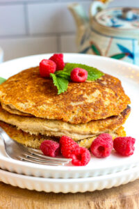 stacked oat flour pancakes ready to eat on a white plate