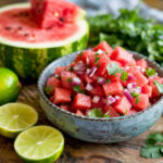 side view of watermelon pico de gallo in serving bowl with lime