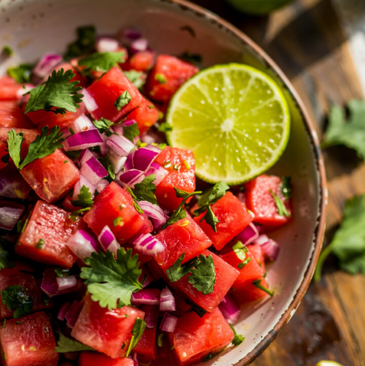 overhead view of watermelon pico de gallo in serving bowl with lime