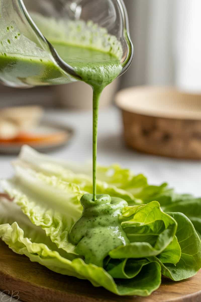 creamy tarragon hemp dressing being poured onto romaine lettuce