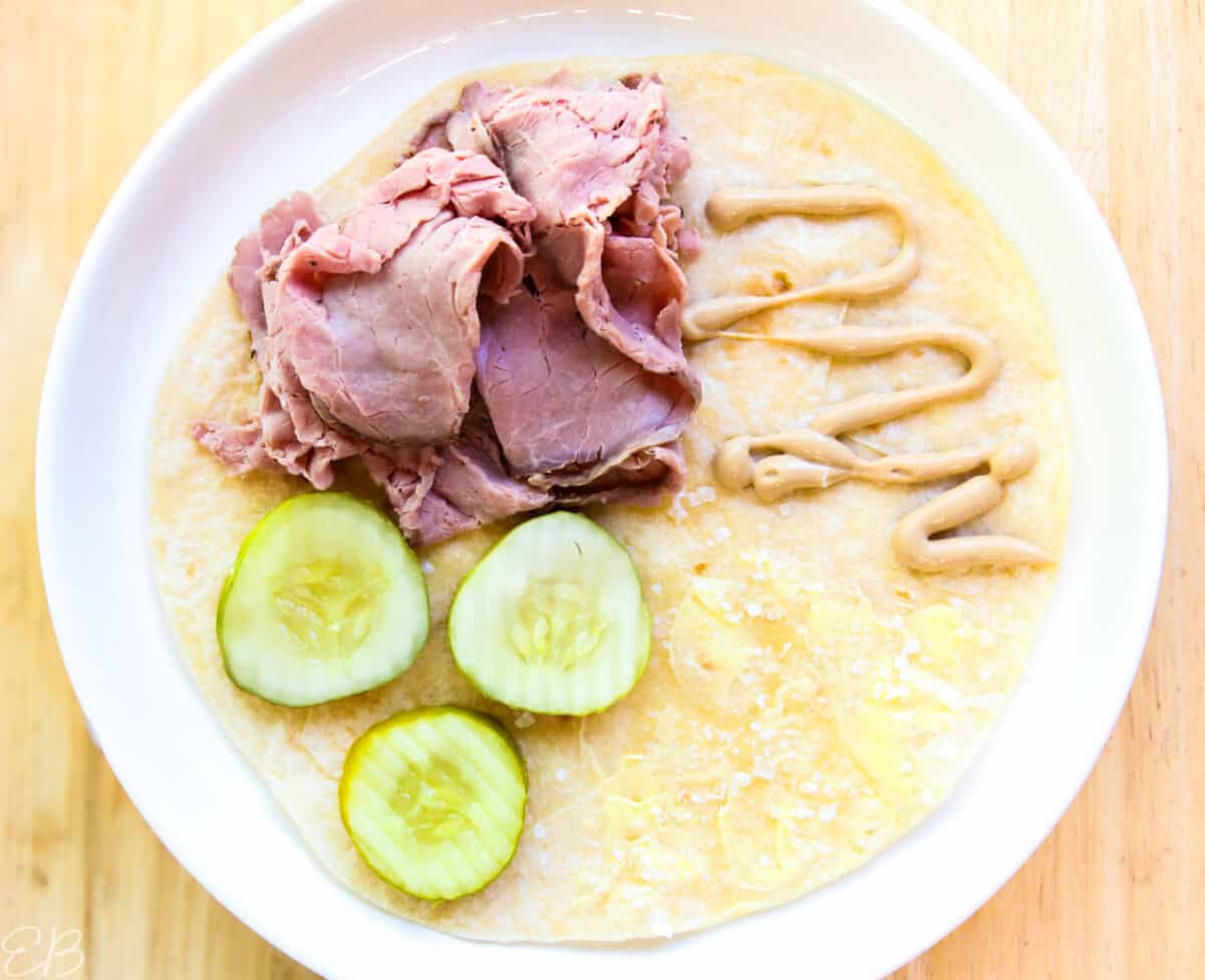 overhead view of roast beef, mustard and pickles sandwich wrap for kids' lunches, not folded yet