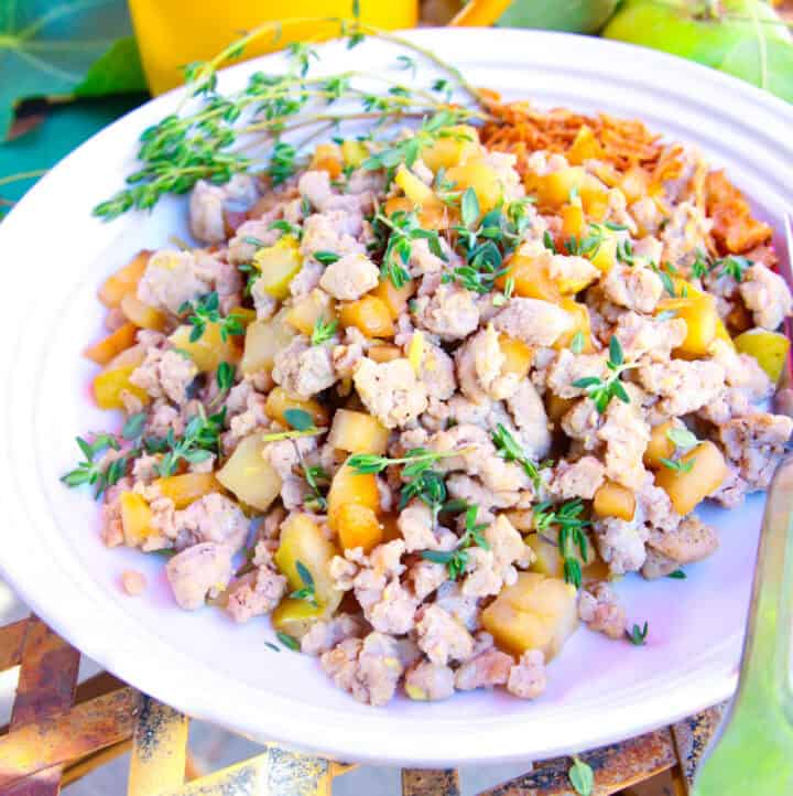 up close angled photo of ground turkey, apple and parsnip hash served for breakfast on a white plate with mug in background