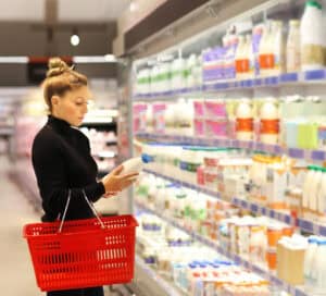 woman checking milk label at grocery store, to see if it has vitamin A palmitate