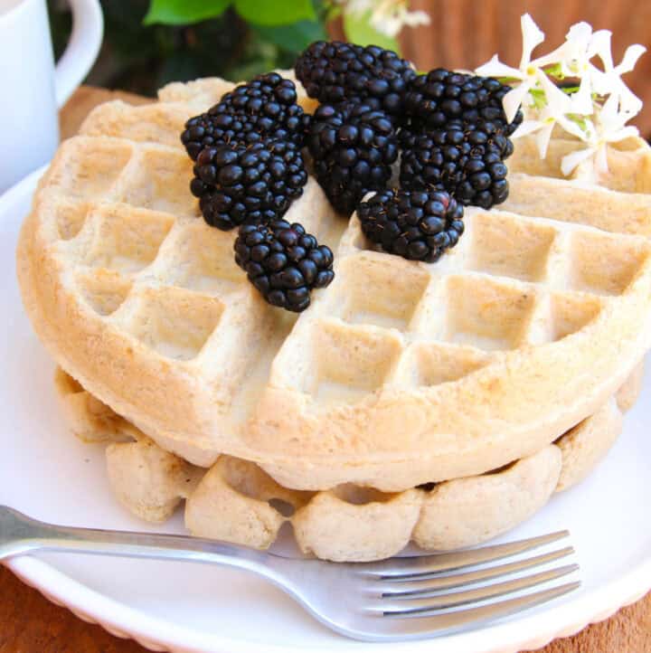 fresh blackberries on oat-flour-sourdough-waffles stacked on a white plate