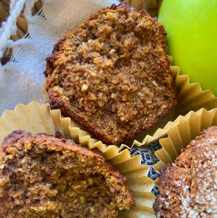 a broken open paleo aip apple cinnamon muffin in basket with apples