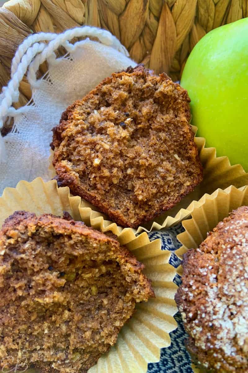 a broken open paleo aip apple cinnamon muffin in basket with apples
