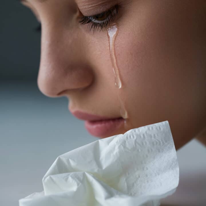 why we produce mucous when we cry: image of woman crying and tissue from blowing one's nose