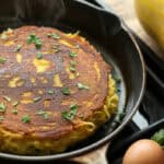 UP CLOSE photo of spaghetti squash pancake just after cooking in pan with ingredients to one side