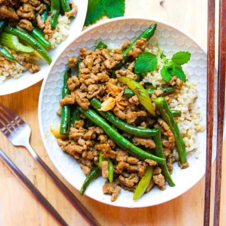 overhead view of thai ground turkey and green beans served in bowls with rice
