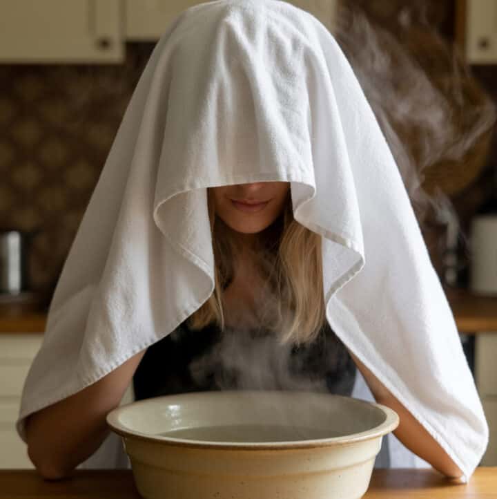 woman leaning over bowl of steamy water, with dish towel
