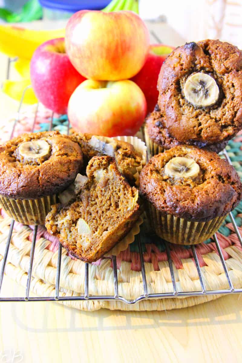 several gf vegan apple spice banana muffins piled up on a cooling rack