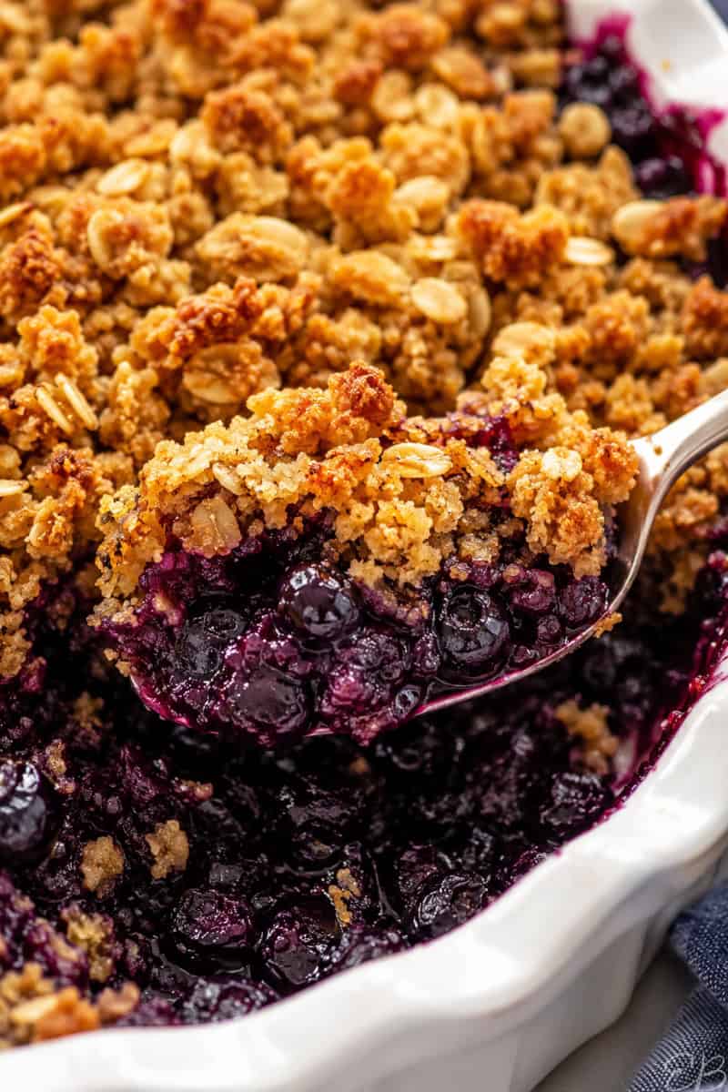 gluten free blueberry crisp with oats being served from a white casserole dish