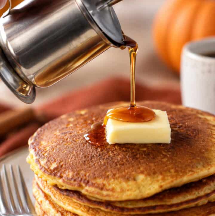 stack of paleo gluten free pumpkin pancakes with syrup being poured on