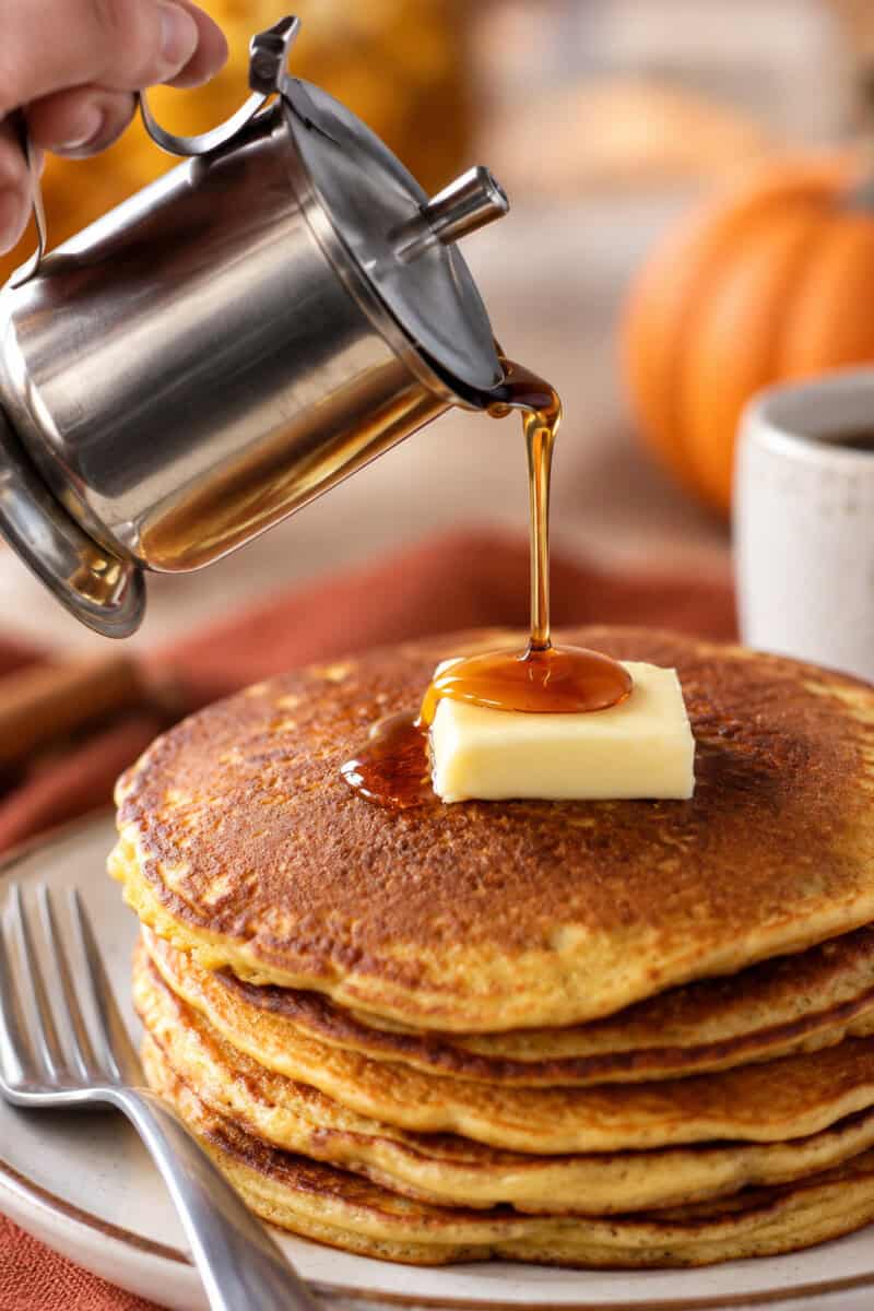 stack of paleo gluten free pumpkin pancakes with syrup being poured on