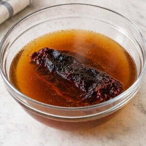 dried ancho chile steaming in broth for enchilada sauce